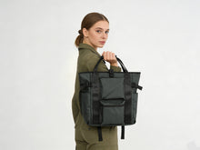 Woman holding a black backpack against a white background
